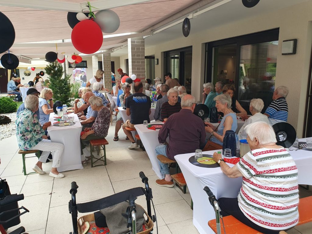 Das Foto zeigt mehrere Bewohnerinnen und Bewohner im Außenbereich bei einer Veranstaltung im Maria Stadler Haus.